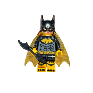 Minifigura de colección de Batichica (Batgirl) de DC Comics sobre un fondo blanco puro. Viste un traje negro con un logo de murciélago amarillo y botas amarillas. Tiene una capa dorada brillante y el pelo largo pelirrojo asomando bajo su máscara negra. Sostiene un Batarang negro en su mano derecha y está parada sobre una base negra.