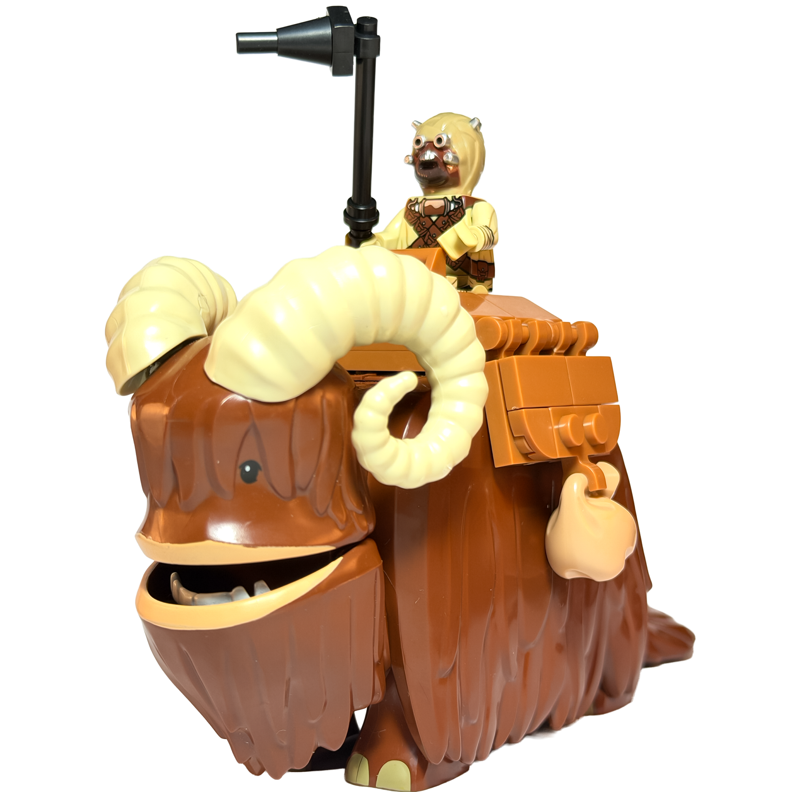 Gran figura de colección de un Bantha de Star Wars con pelaje marrón y grandes cuernos curvos blancos. Sobre su montura cabalga una minifigura de un Morador de las Arenas (Tusken Raider) con su clásica máscara de vendajes, sosteniendo en alto un arma negra (Palo Gaffi). Todo presentado sobre un fondo negro sólido.